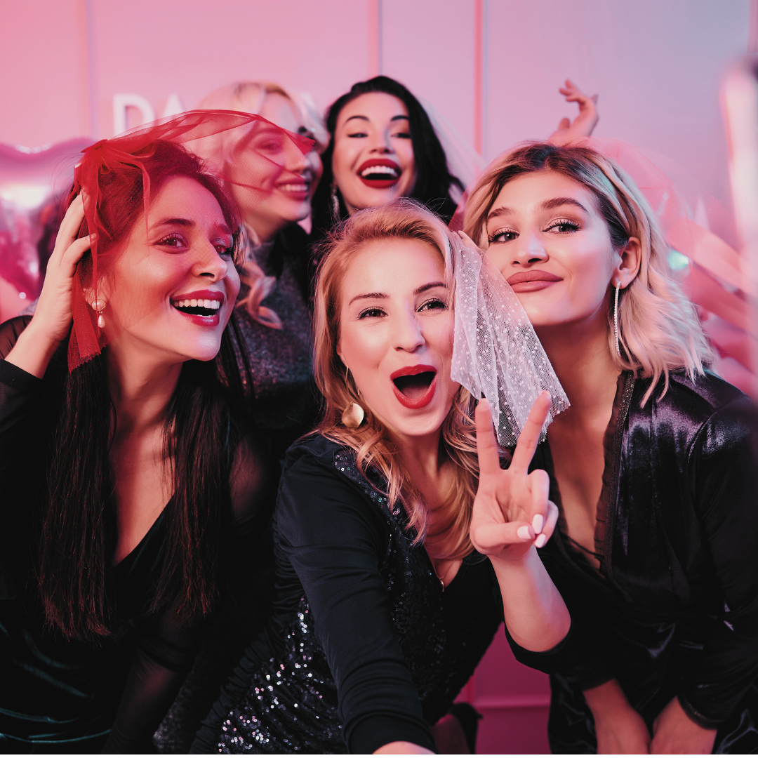 Five women taking a selfie at a bachelorette party, all dressed in black